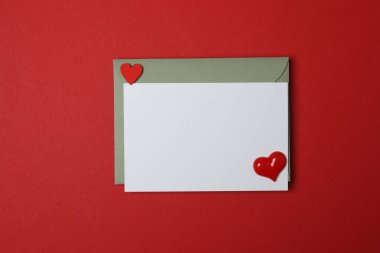 Sevgililer Günün kutlu olsun. Tebrik kartı ve kırmızı arka planda dekoratif kalp ile zarf, üst görünüm