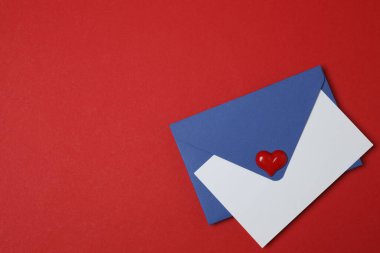 Sevgililer Günün kutlu olsun. Tebrik kartı ve kırmızı arka planda dekoratif kalp ile zarf, üst görünüm