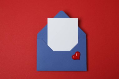 Sevgililer Günün kutlu olsun. Tebrik kartı ve kırmızı arka planda dekoratif kalp ile zarf, üst görünüm