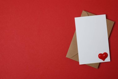 Sevgililer Günün kutlu olsun. Tebrik kartı ve kırmızı arka planda dekoratif kalp ile zarf, üst görünüm