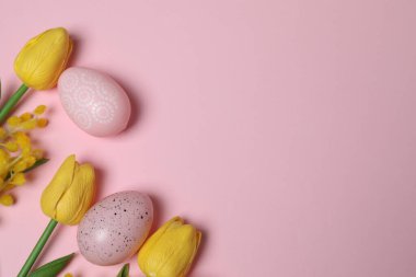 Parlak Paskalya kompozisyonu pastel yumurta figürleri ve pembe arka planda parlak çiçekler, heyecan verici şenlik havası ve bahar selamlaması.
