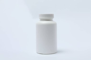 Beyaz arka planda haplar olan ilaç şişesi..