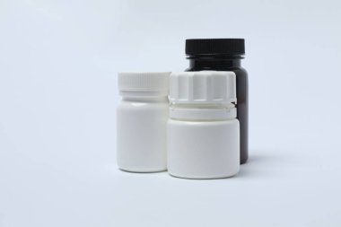 Beyaz arka planda haplar olan ilaç şişesi..