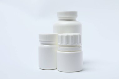 Beyaz arka planda haplar olan ilaç şişesi..