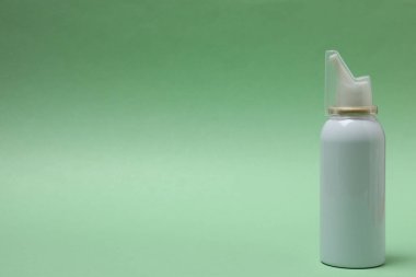 Yeşil arka planda beyaz plastik sprey şişesi.