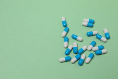 Yeşil arka planda haplar olan ilaç şişesi..