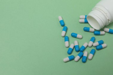 Yeşil arka planda haplar olan ilaç şişesi..