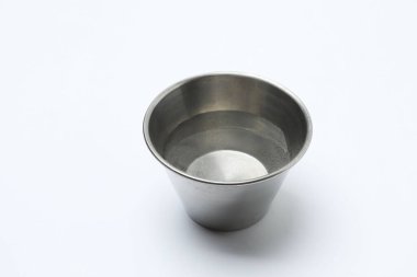 Beyaz zemin üzerinde su olan demir bir kap.