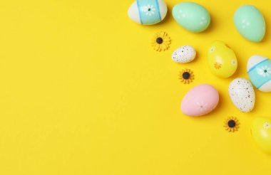 Parlak Paskalya kompozisyonu pastel yumurta heykelcikleri ve sarı arka planda parlak çiçekler, keyifli bir şenlik havası ve bahar selamlaması.