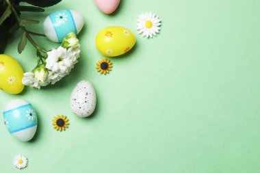 Parlak Paskalya kompozisyonu pastel yumurta heykelcikleri ve yeşil arka planda parlak çiçekler büyüleyici bir şenlik havası ve bahar selamlaması.