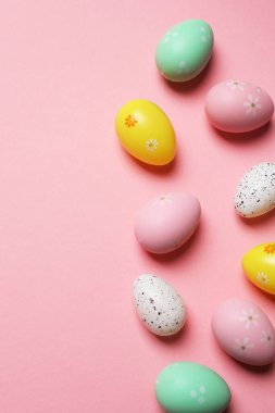 Parlak Paskalya kompozisyonu pastel yumurta figürleri ve pembe arka planda parlak çiçekler, heyecan verici şenlik havası ve bahar selamlaması.