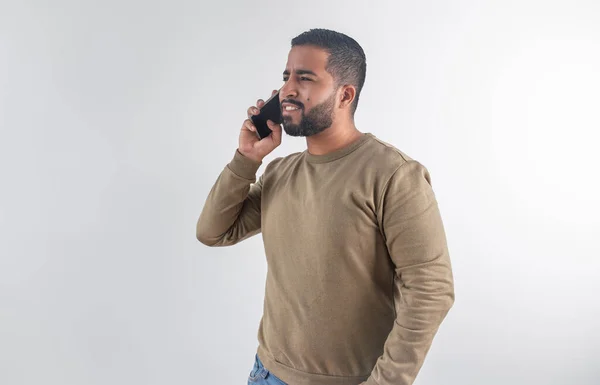 Telefonda süveter giyen gülümseyen genç bir adam, beyaz bir geçmişle meşgul görünüyor.