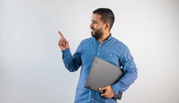 Gülümseyen iş adamı elinde bir dizüstü bilgisayarla tanıtım için fotokopi alanına doğru hareket ediyor.