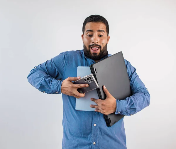 Dizüstü bilgisayar, tablet ve akıllı telefonu tutmaya çalışan şok olmuş bir ifadeyle bunalmış bir adam.