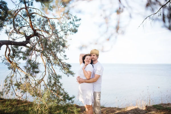 En man kramar en flicka på stranden i en tallskog under en resa. — Stockfoto