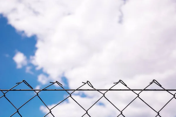 De uma grade metálica ao céu azul com nuvens brancas — Fotografia de Stock