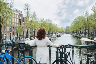 Amsterdam 'da bir su kanalının üzerinde duran genç ve güzel bir kadın.