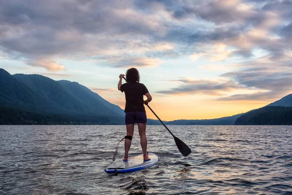 夕日の景色の湖での女性のパドルボーディング — ストック写真