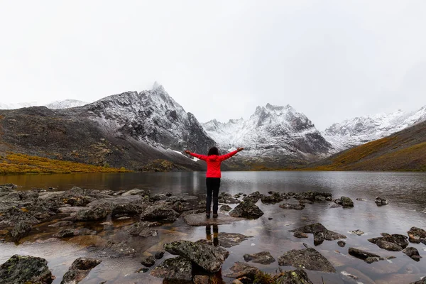 Menina de pé no lago com montanhas nevadas — Fotografia de Stock