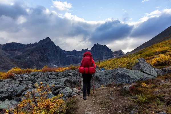 Mochilero mujer en sendero panorámico rodeado de montañas resistentes — Foto de Stock