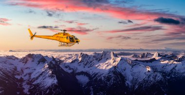 Sarı helikopter Rocky Dağları üzerinde uçuyor.