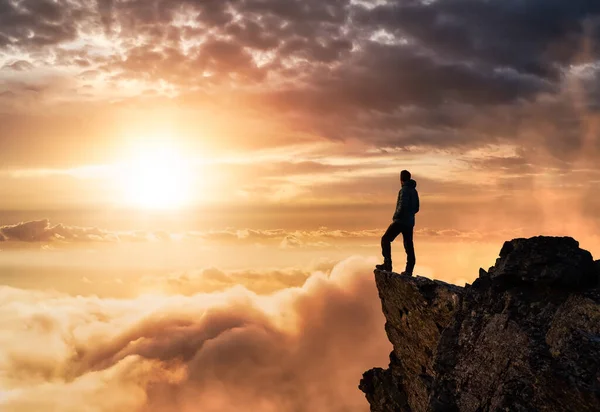 Kayalık bir dağın tepesinde yürüyen adamın Sihirli Fantezi Macerası bileşimi