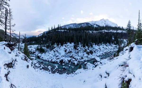 Kanada doğasındaki güzel buzul nehri kış günbatımında dağlarla çevrilidir. — Stok fotoğraf