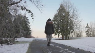 Kız sisli kış gündoğumunda parkta yürüyor