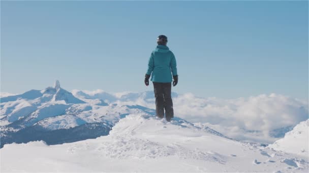 Avontuurlijk meisje bovenop een prachtige besneeuwde berg tijdens een levendige en zonnige winterdag. — Stockvideo