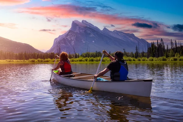 Pareja de amigos aventureros están paseando en canoa en un lago rodeado por las montañas canadienses. —  Fotos de Stock