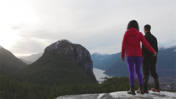 Pareja aventurera Senderismo en las montañas durante un soleado atardecer de invierno. — Vídeo de stock