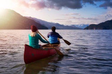 Ahşap bir kanoda kano süren iki arkadaş.