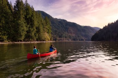 Ahşap bir kanoda kano süren iki arkadaş.