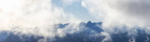 Stryktåliga bergstoppar täckta av snö och moln — Stockfoto
