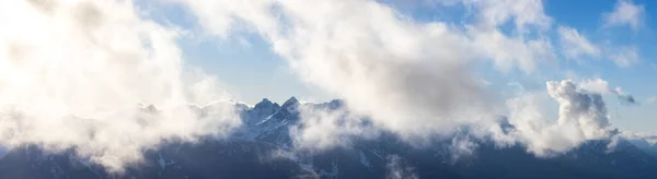 Karla kaplı engebeli dağ tepeleri ve bulutlar — Stok fotoğraf