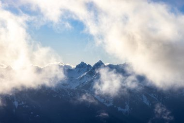 Karla kaplı engebeli dağ tepeleri ve bulutlar