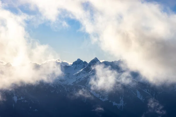 Zerklüftete Berggipfel in Schnee und Wolken gehüllt — Stockfoto