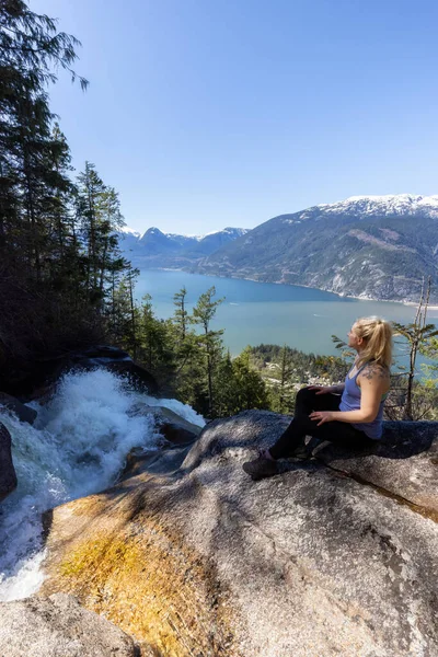 Adventurous Adult Woman is sitting on top of a Beautiful Waterfall — Stock Photo, Image