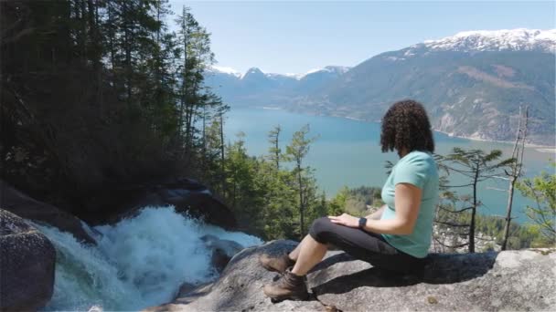 Adventurous Adult Adult Woman is sitting on top of a Beautiful Waterfall — стоковое видео