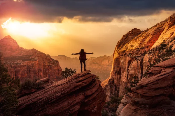 Äventyrlig kvinna vid kanten av en klippa tittar på ett vackert landskap — Stockfoto