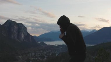 Siyah kapüşonlu beyaz adam gölge boksu yapıyor.