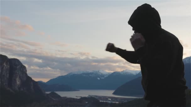 Caucásico Hombre usando una sudadera con capucha negra practicando boxeo en la sombra — Vídeos de Stock