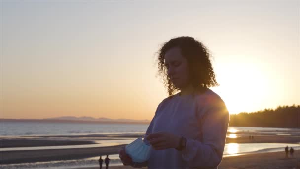 Blanke blanke vrouw uit de middeleeuwen buiten op het strand met gezichtsmasker — Stockvideo