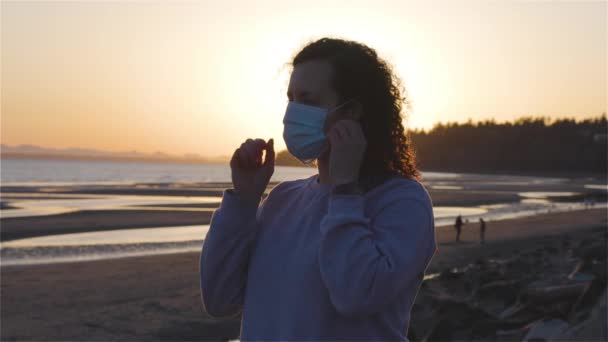 Vit kaukasisk medeltid kvinna utanför på stranden tar av Face Mask — Stockvideo