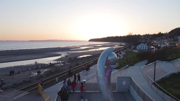 Mensen genieten van de prachtige zonsondergang aan het strand bij de kade — Stockvideo
