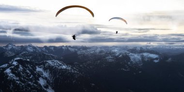 Rocky Dağları 'nda yükselen Paraglider' ın Macera Birleşmiş Görüntüsü. Güneşli Günbatımı Gökyüzü. British Columbia, Kanada 'dan Hava Arkaplanı. Ekstrem Spor Konsepti. Panorama