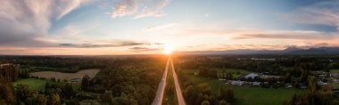 Fraser Vadisi 'ndeki Trans-Canada Otoyolu' nun renkli bahar günbatımında hava panoramik görüntüsü. Büyük Vancouver, İngiliz Kolombiyası, Kanada.