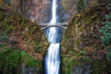 View of a bridge going over a river with Multnomah Falls in the background. Colorful Art Render. Located near Portland, Oregon, United States. clipart