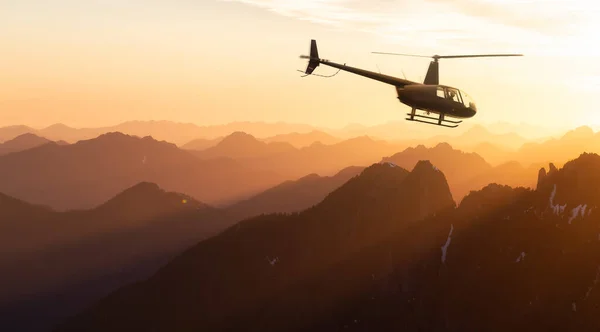 Helicóptero preto voando sobre as Montanhas Rochosas canadenses. — Fotografia de Stock