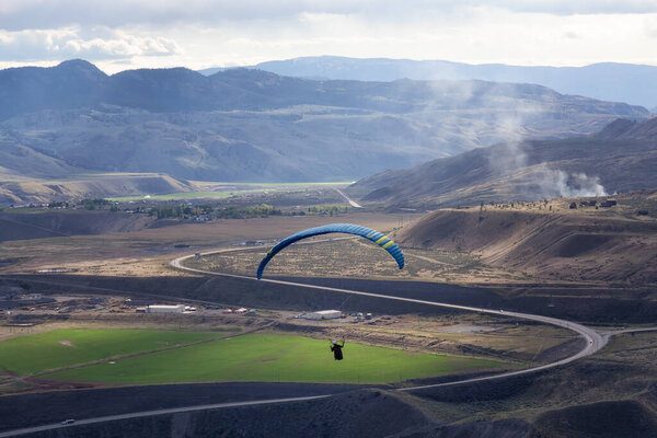 Adventurous Man Flying on a Paraglider around the mountains.